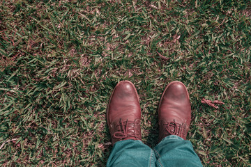 first person view of man feet with old shoes brown on the grass