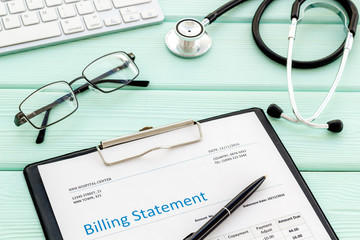 phonendoscope, billing statement and keyboard on work desk of doctor in hospital mint green background