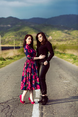 two young twins sisters in the middle of road in colorful dress with flowers