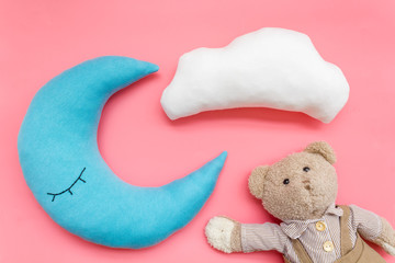 Moon pillow, clouds and teddy bear for put newborn in bed on pink background top view