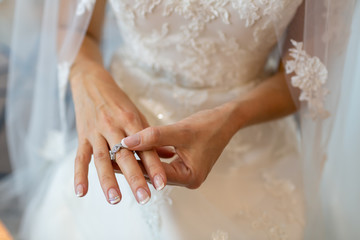 The bride in a wedding dress with a veil wearing a silver ring on the middle finger.