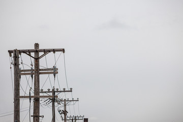 Electric and telephone power line, old and outdated, on a rotten wooden pole, abiding by North...