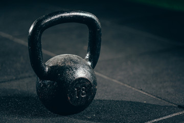 Naklejka na ściany i meble Black heavy kettlebell on gray floor, weightlifting