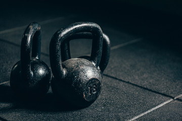 Fototapeta premium Black heavy kettlebells on gray floor, weightlifting