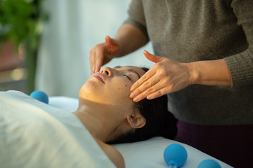 Young Woman receiving facial massage in spa wellness center