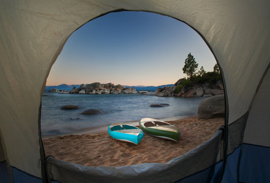 A View Through A Tent Door Of Two Paddle Boards Sitting On A Beach.