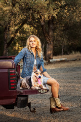 Country girl sitting on the tail gate of her pickup with a cattle dog.