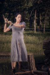Country girl wearing work boots and a dress chopping wood on a ranch.