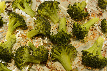 Close up of roasted broccoli florets sprinkled with garlic powder on aluminum foil