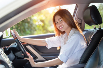 Young Asian woman driver driving a car on the road in countryside.
