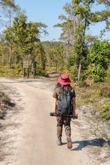 Woman traveler with backpack holding hat at mountains and Tropical forest. Female photographer outdoors in nature, travel holiday relaxation conceptt, space for text, atmospheric