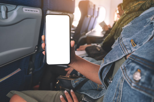 Mockup image of woman holding and showing a black smart phone with blank desktop screen in cabin