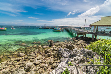 Obraz premium Wooden bridge walkway Rock the beach to the pier to transport tourists on the island on a clear day.