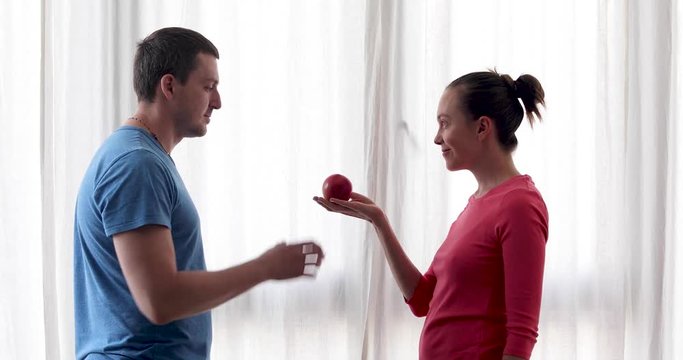 Woman gives apple to man. Man eats an Apple
