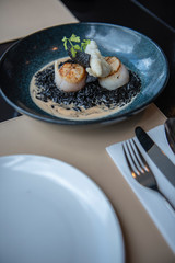 Sea shell served with Italian black rice with gravy. Served as a main course in a modern French restaurant in Bangkok, Thailand.
