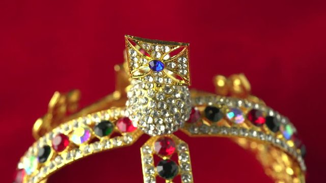 Gold diamond crown or decorative pageant accessory close up focus on the top. Slowly rotation on the red royal color surface. 4k, uhd.
