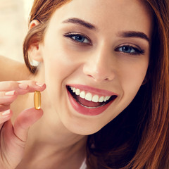 Woman with Omega 3 fish oil capsule, at home