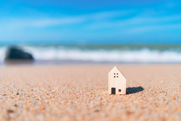 Obraz na płótnie Canvas Small home model on sand beach with blue sky background.