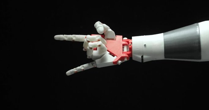 Smart robotic programmed prosthesis hand shows rock gesture, victory and ok sign on black background. Palm hand close-up.