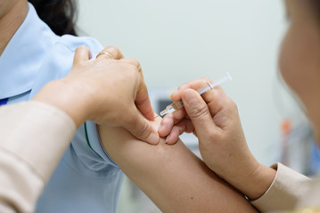 Close up doctor's hand injecting for vaccination in the shoulder woman patient.Vaccine for protection concept 