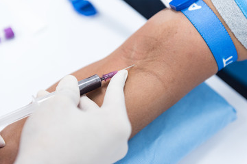 Obraz premium Close up nurse pricking needle into the patient arm for blood chemistry test.Laboratory with technician collecting a blood sample from patient.Medical analysis concept