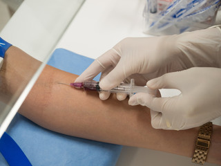 Close up nurse pricking needle into the patient arm for blood chemistry test.Laboratory with...