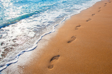 beach, wave and footprints at sunset time