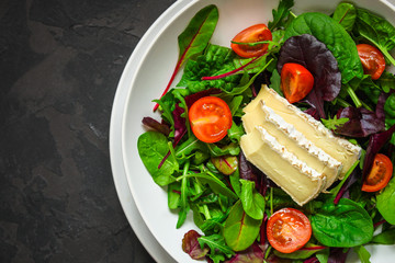 Healthy salad, leaves salad mix in a white plate and cheese (green, juicy snack). food background - Image