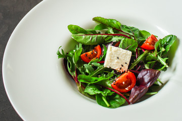 Healthy salad, leaves salad mix in a white plate and cheese (green, juicy snack). food background - Image