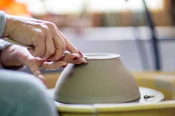 Fototapeta na wymiar Artist make pot of mug at pottery wheel with hands