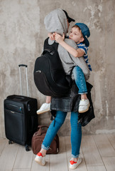 mother carries a small son on a suitcase in the waiting room of transport.