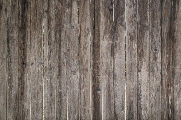Full frame background of an old, faded and scratched brown wooden board wall or fence.