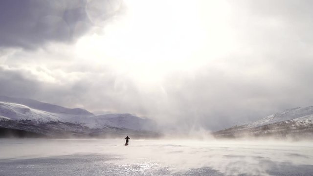 Woman cross-country skiing while the wind is blowing over a frozen river in Sarek. Lapland, Sweden.