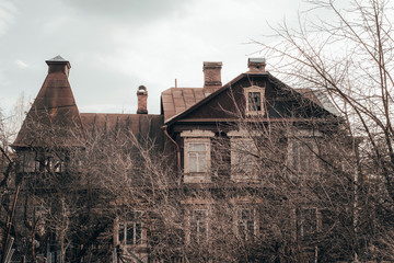 Creepy old manor in the forest against a gray sky