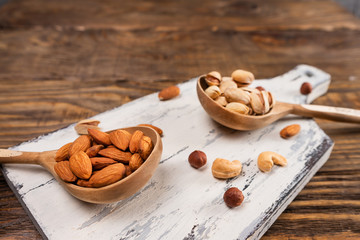 Nuts in wooden spoons on a dark wooden table.