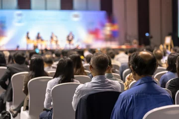 Rear view of Audience listening Speakers on the stage in the conference hall or seminar meeting, business and education about investment concept © THANANIT