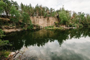 Landscape of an old flooded industrial granite quarry filled with water. Lake on the background of rocks and fir trees. Canyon The nature of the autumn. Place for text and design.