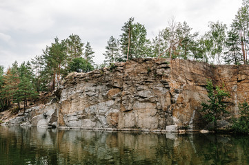 Fototapeta na wymiar Lake on the background of rocks and fir trees. Canyon. The nature of autumn. Place for text and design. Landscape of an old flooded industrial granite quarry filled with water.