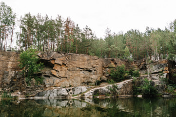 Fototapeta na wymiar Lake on the background of rocks and fir trees. Canyon. The nature of autumn. Place for text and design. Landscape of an old flooded industrial granite quarry filled with water.