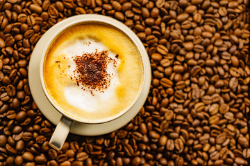 Cappuccino cup on roasted coffee beans.