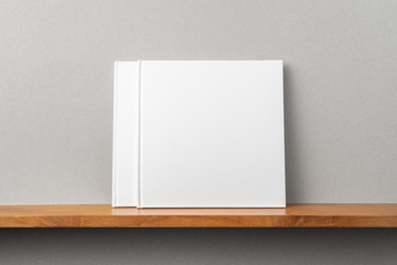 2 white square notebook on bookshelf and grey wall