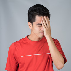 Sick young man handsome and headache wearing a red shirt isolated on gray wall background. Concept Of headache. Asia people.