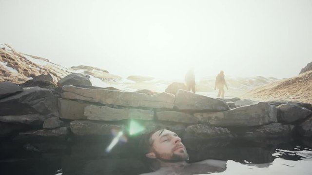 Happy man relax in geothermal hot pool in Iceland