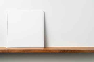 white square notebook on bookshelf and white wall