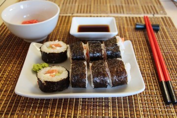 Set of sushi rolls makizushi, also known as norimaki or makimono, with cucumber and salmon on a bamboo mat known as a makisu. Sushi, Japanese cuisine, Food and drink concept.