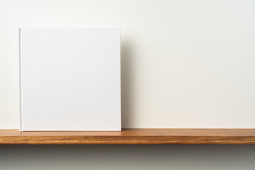 white square notebook on bookshelf and white wall © voyata