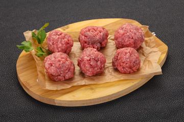 Raw meatball over wooden background