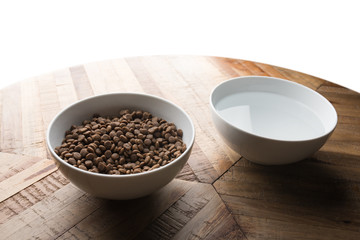 cat  food dishes - two white bowls of cat  dry food and water standing on a wooden table in front of white background