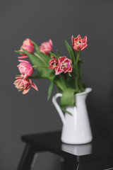 A bouquet of pink peony tulips in a white jug.