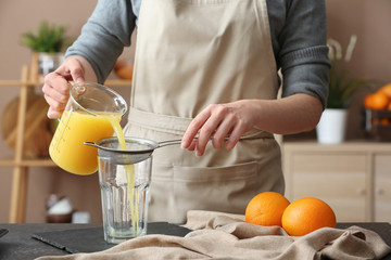 Woman preparing orange juice in kitchen